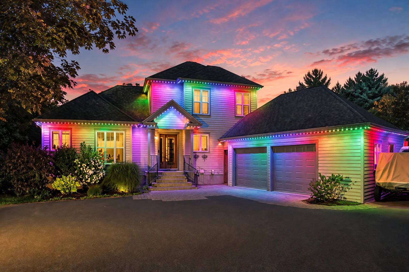 Modern two-storey home at night, roofline and columns outlined in red and green, entry steps lit to match