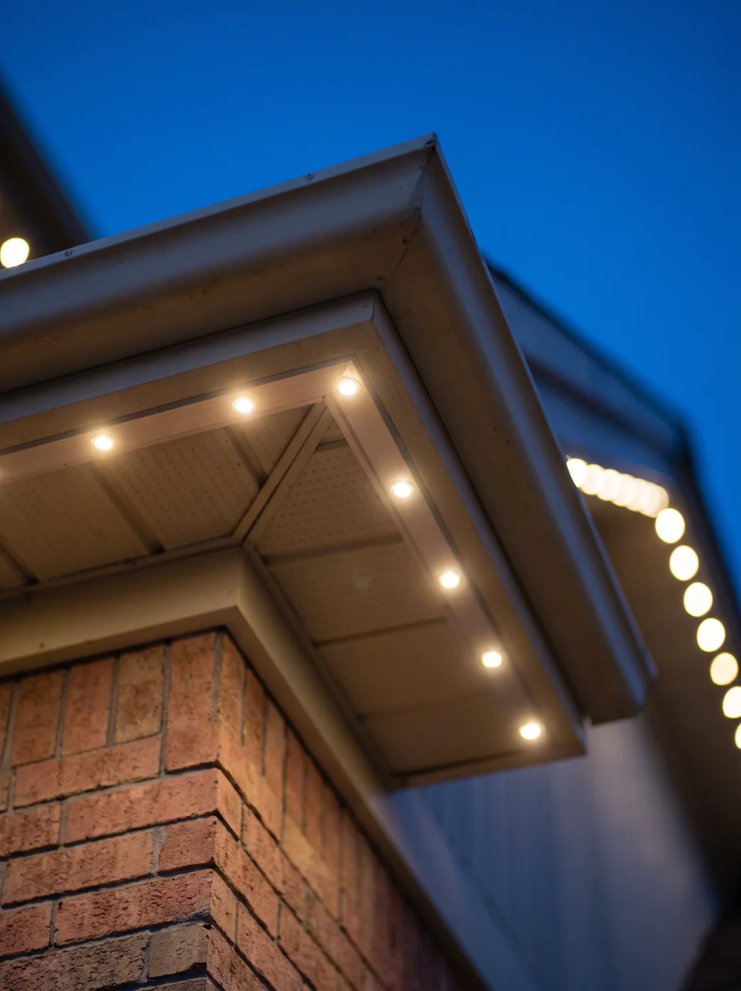 Individual point-light LED fixtures set into a soffit corner, each glowing warm white at dusk — the pixel product line