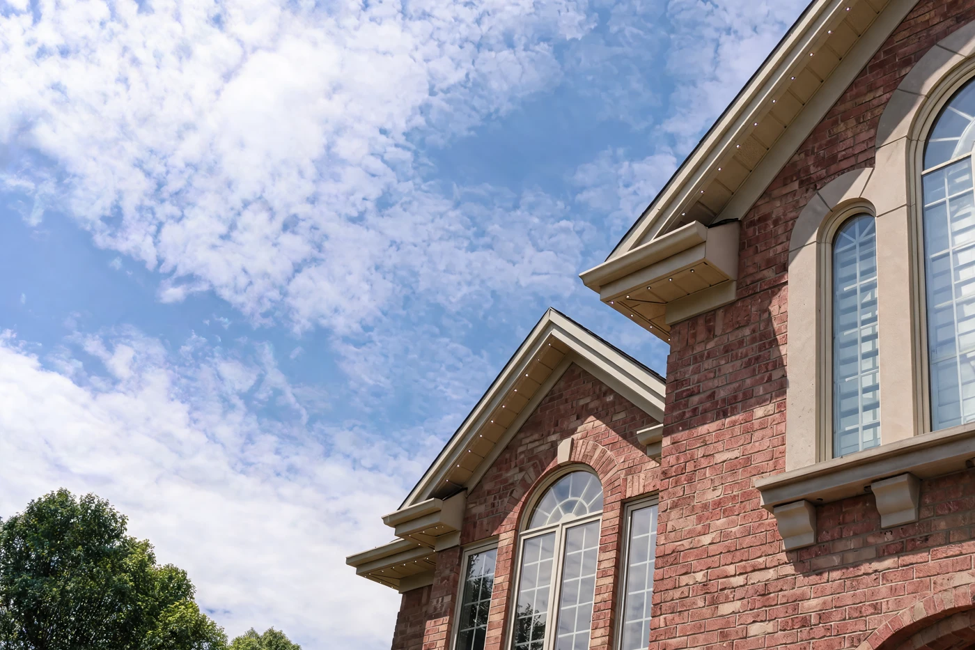 The roof peaks of a brick home in daylight, with the lighting rail set into the soffit edge and barely visible