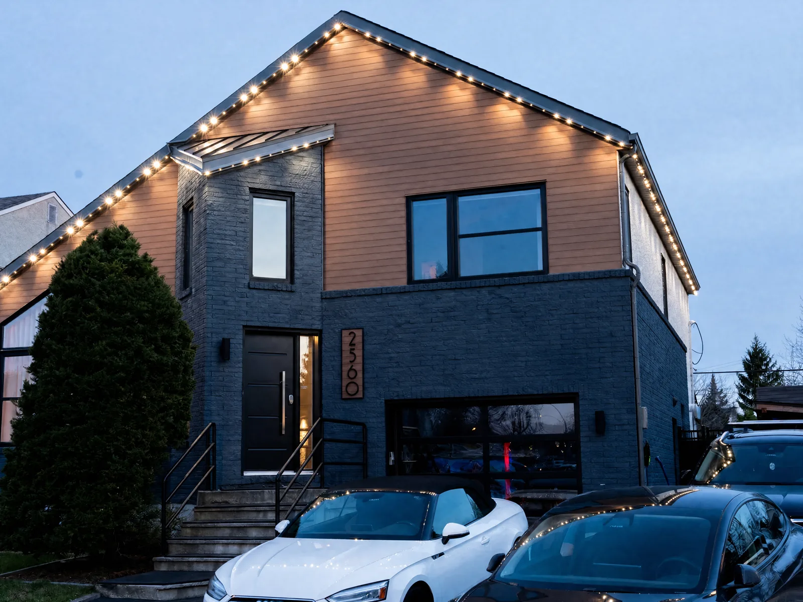 Two-storey home at dusk with warm-white permanent LED lighting tracing the roofline and gable peak — a Montréal-area residence
